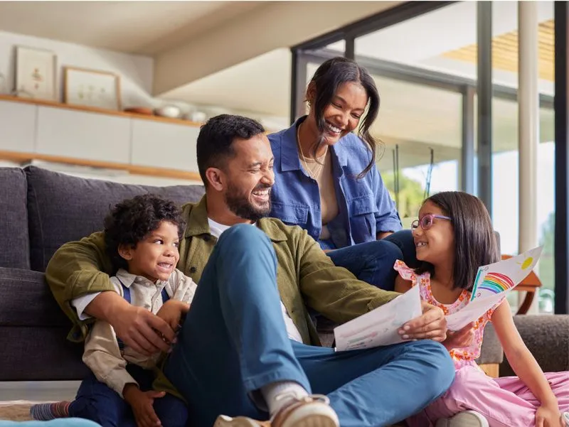 Parents and two children enjoying a book together at home.