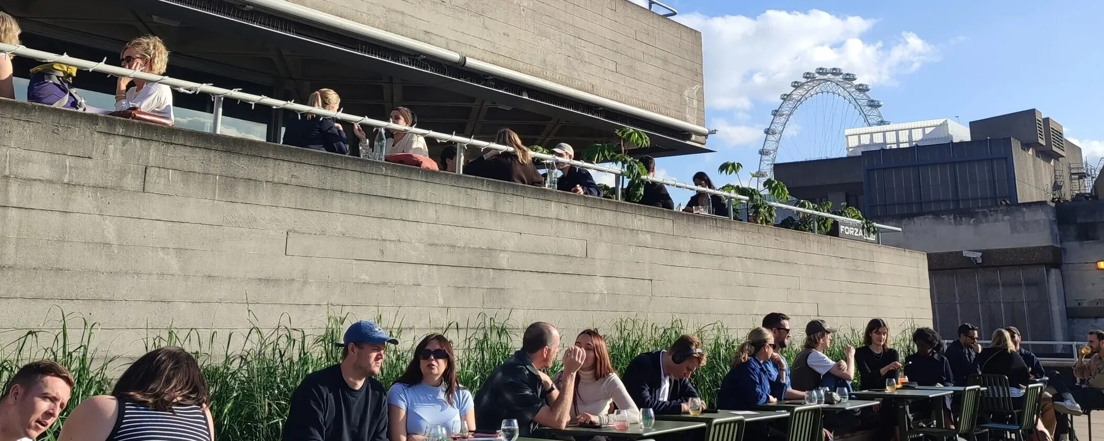 Guests at tables on the Weston Terrace at Forza Taps, National Theatre, with the London Eye behind