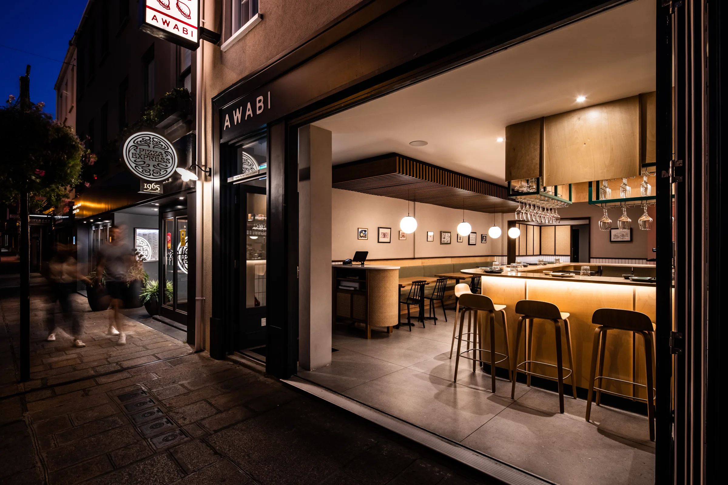 Open shopfront of Awabi at night, showing the lit timber bar inside, Halkett Place, St Helier