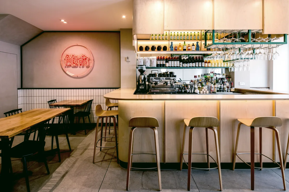 Pale timber bar with stools and a red neon sign at Awabi restaurant, St Helier, Jersey