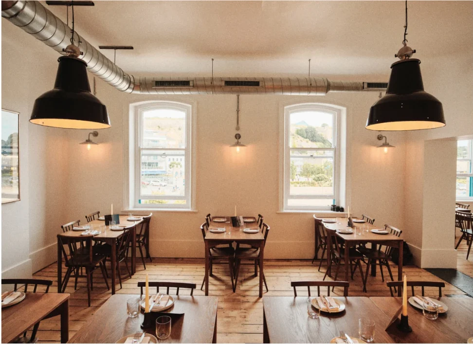 Pêtchi dining room with large black pendant lights, arched windows and timber floors, Liberty Wharf, St Helier