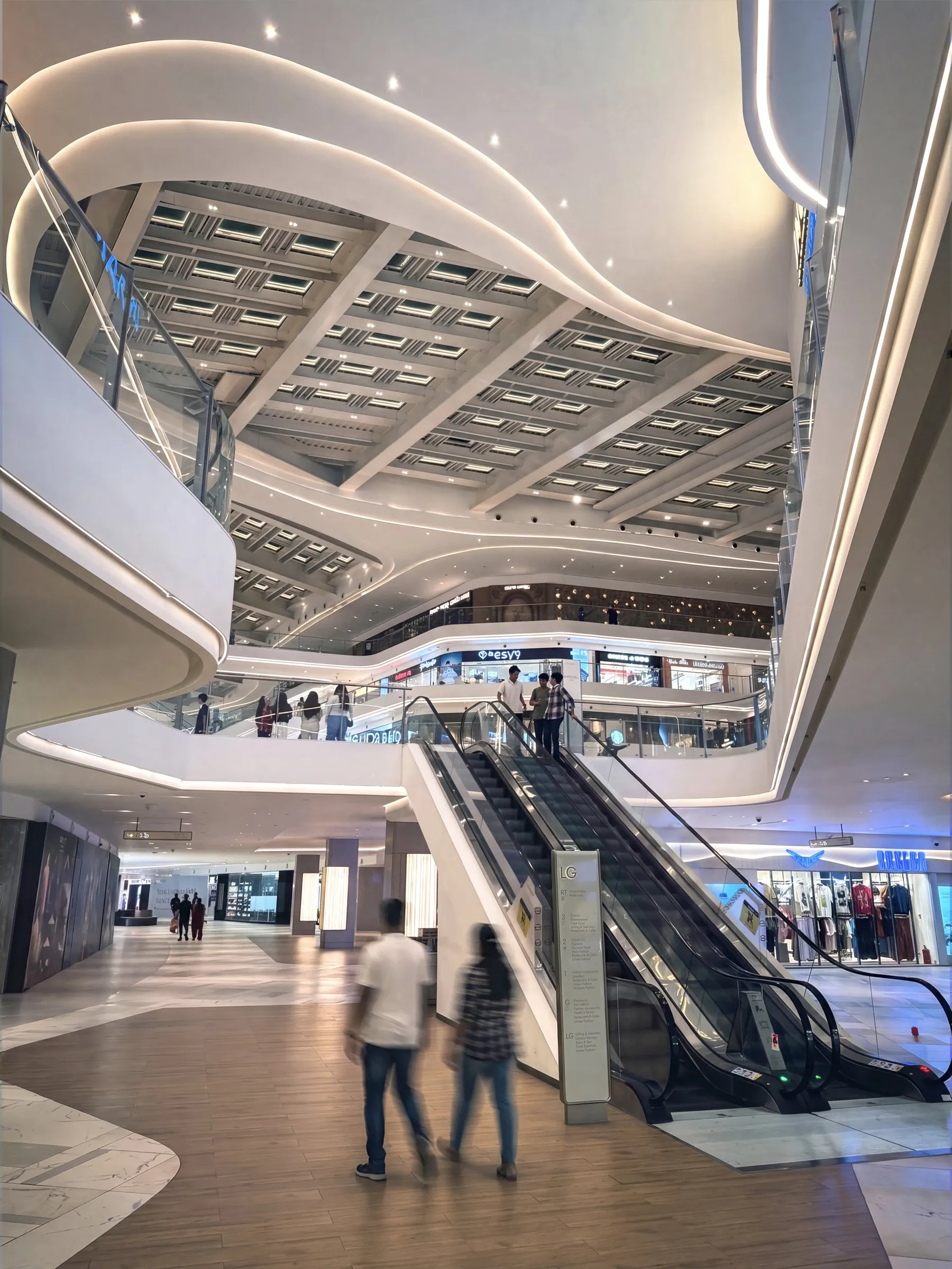 Escalators rising through the curved white levels of the SkyCity Mall atrium