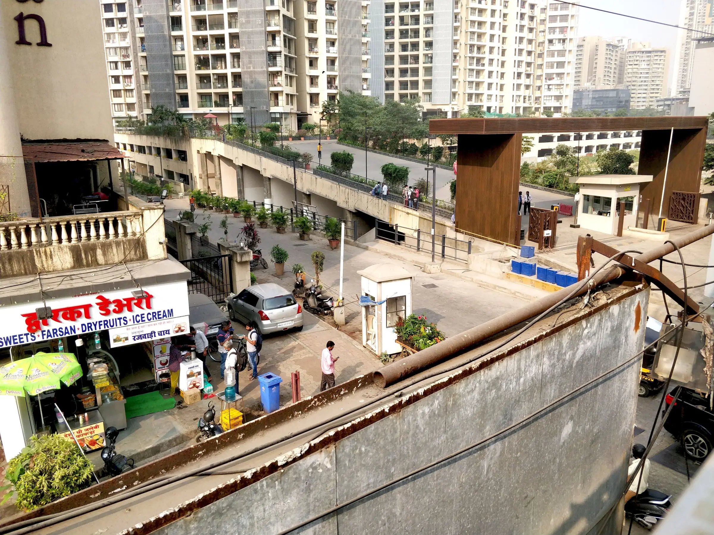 The existing Rivali Park site before redevelopment, with roadside shops and towers behind, Mumbai