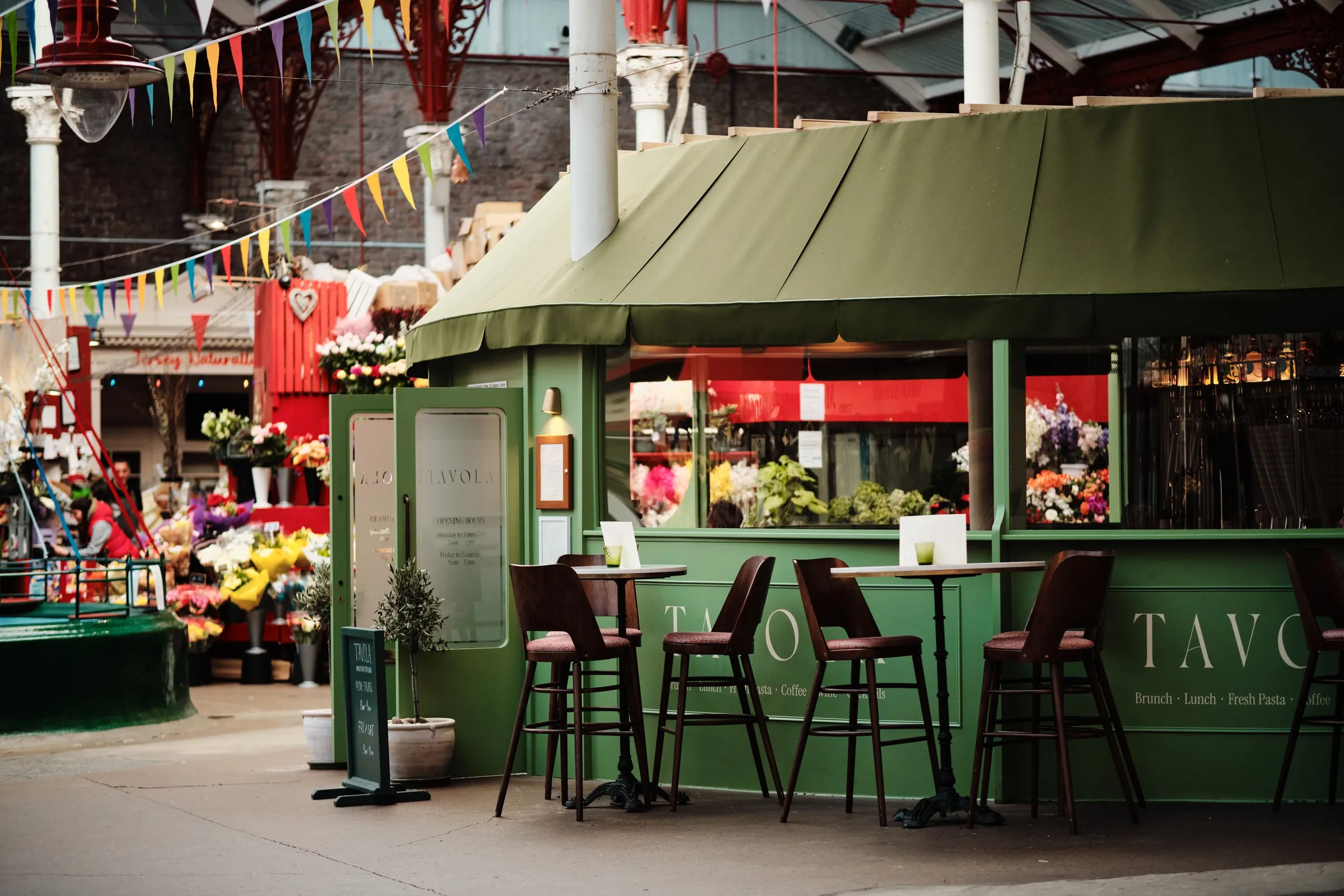 Tavola's green kiosk cafe with bar stools and bunting inside Jersey's Central Market, St Helier