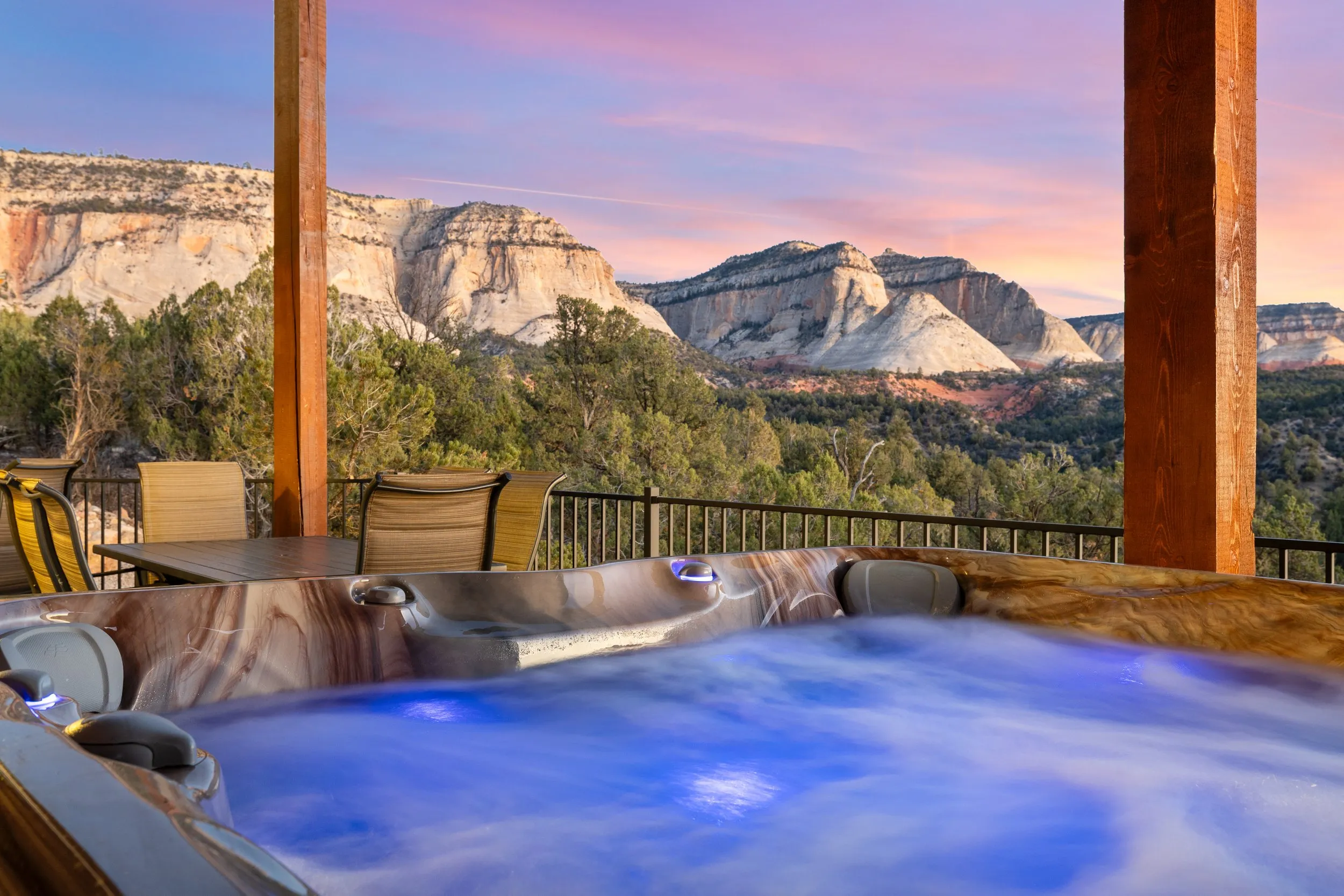Hot tub on a covered deck facing sandstone cliffs at sunset