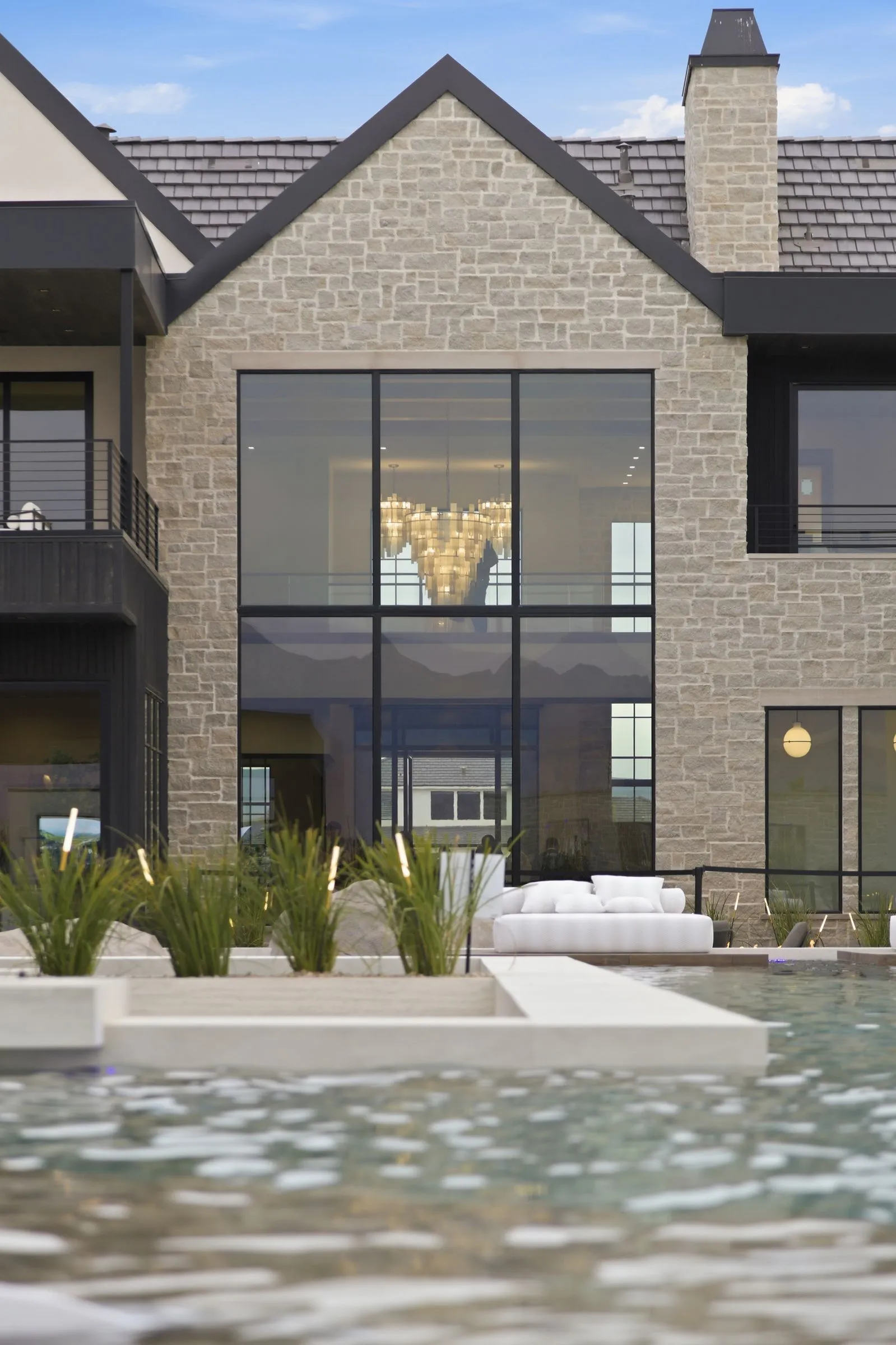 Stone exterior with tall windows reflected in a pool