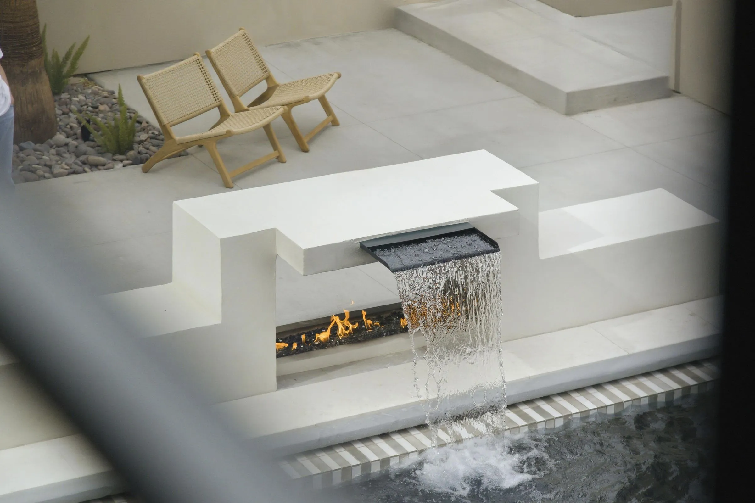 Fire feature and waterfall beside a pool deck