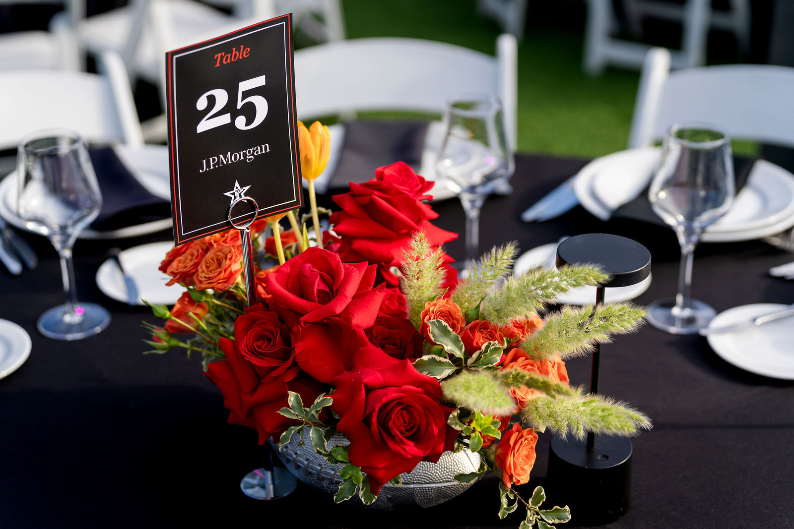 A red floral centerpiece and table number on a set dining table