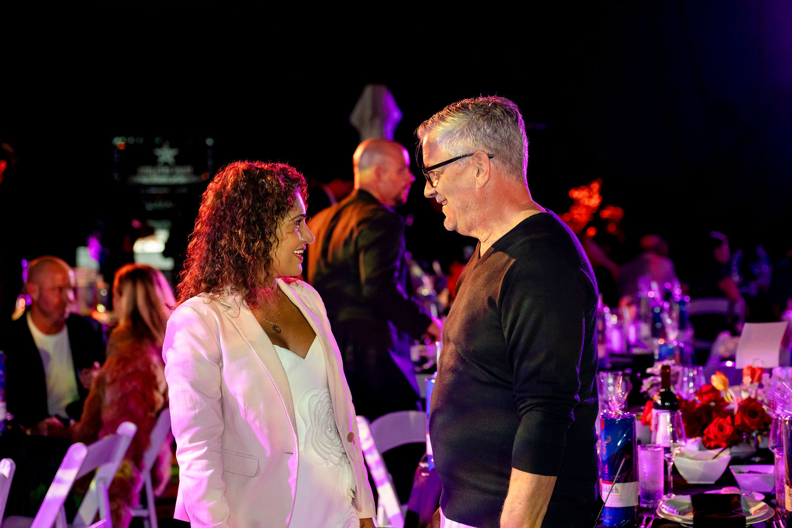 Guests talking under colorful event lighting