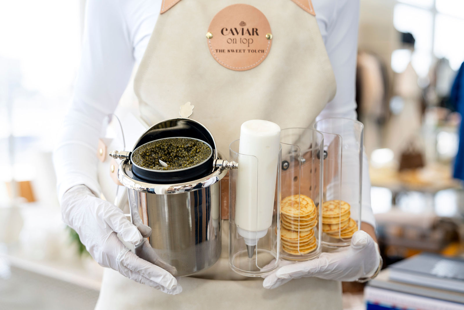 A server in white gloves presenting caviar service