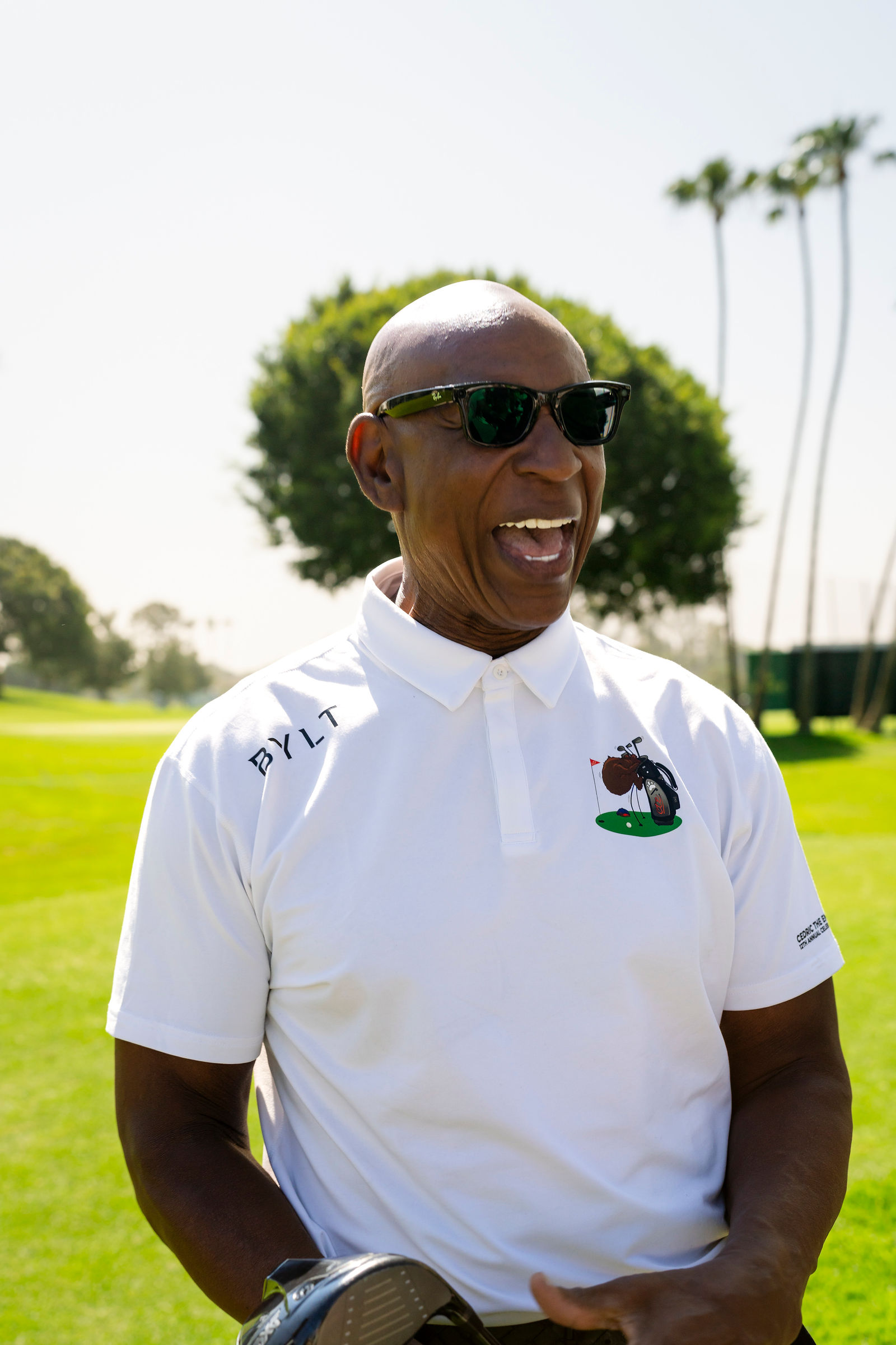 A smiling golfer in a white polo on the course