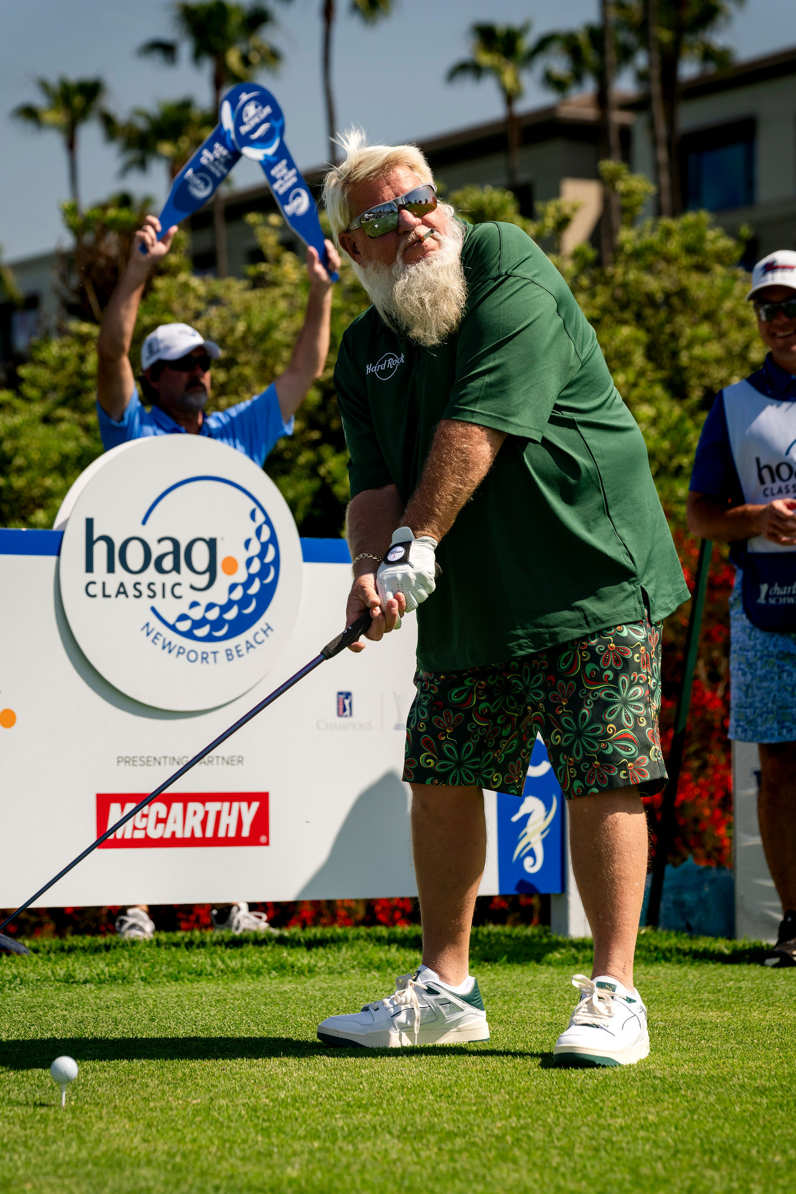 John Daly in green teeing off at the Aston Martin Pro-Am