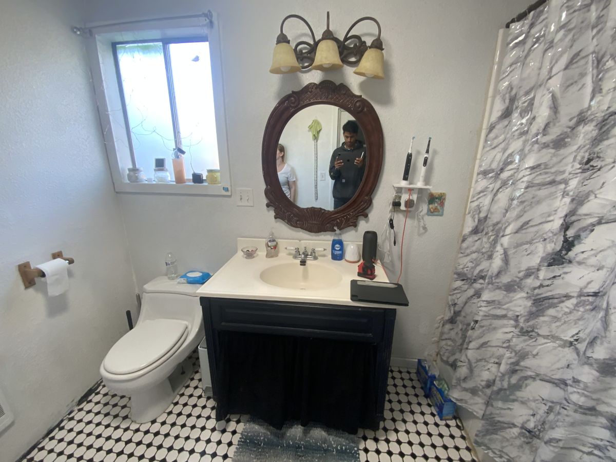 Bathroom before the Ultra Renovations remodel, with a dark vanity and shower curtain