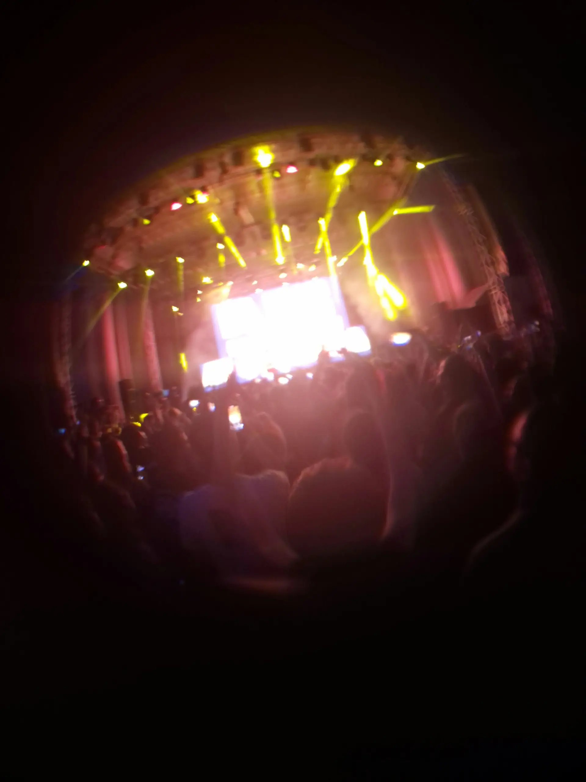 Festival crowd facing a main stage lit with yellow and red beams