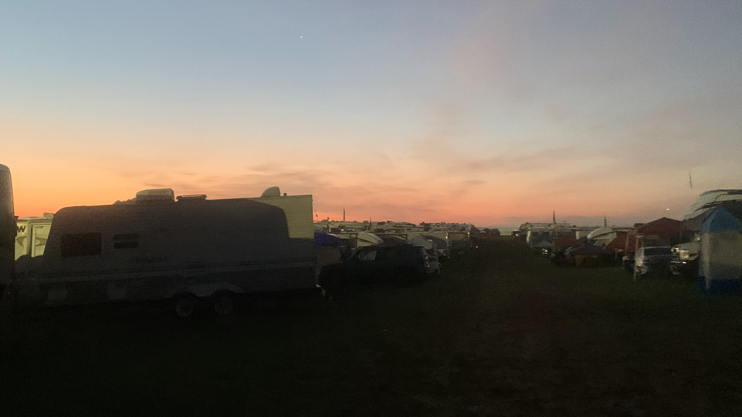 Sunset over a festival campground with RVs and tents