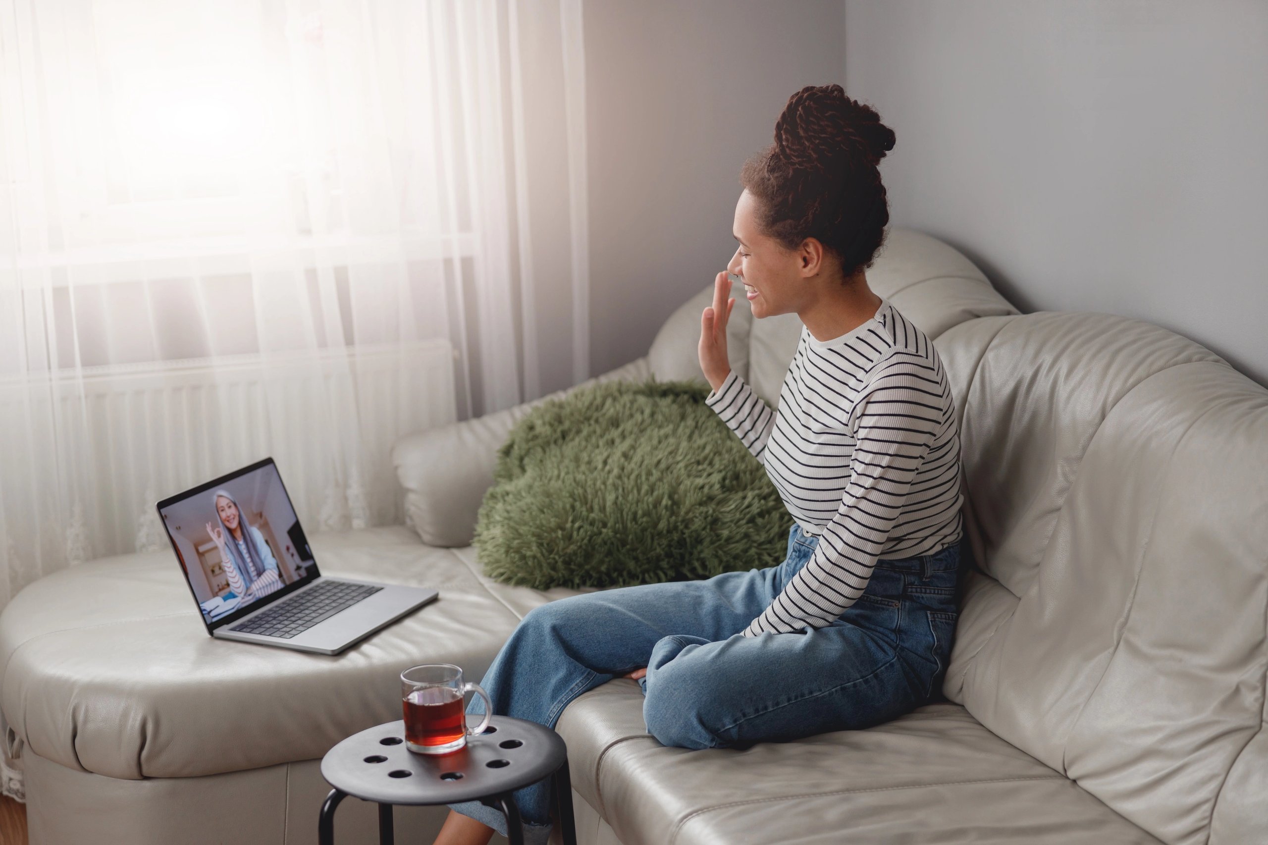 Woman relaxing on a couch during a telehealth session on her laptop