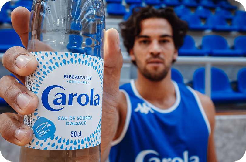 Joueur de basket tenant une bouteille d’eau de source Carola