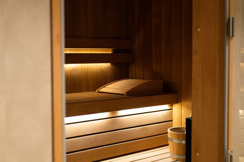 Le sauna finlandais de DAO Verviers : bancs de bois clair éclairés et seau en bois