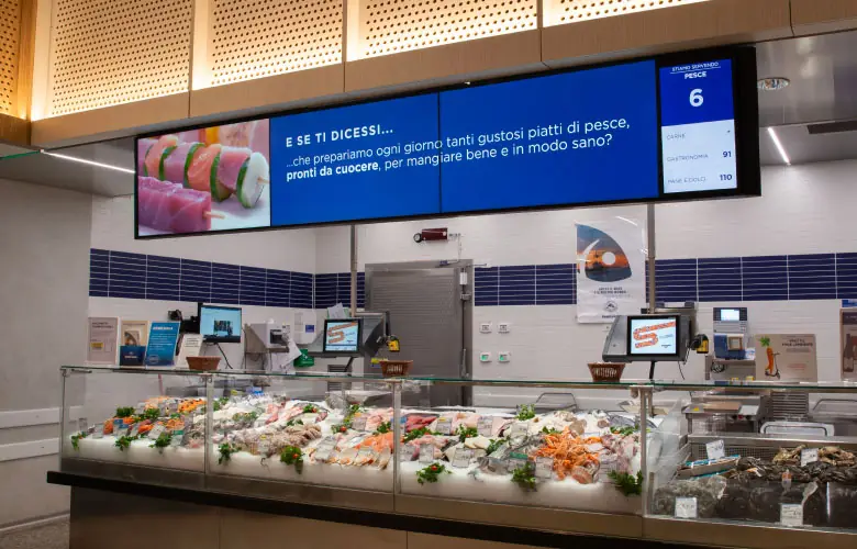 Schermi digitali sopra il banco pescheria di un supermercato Esselunga