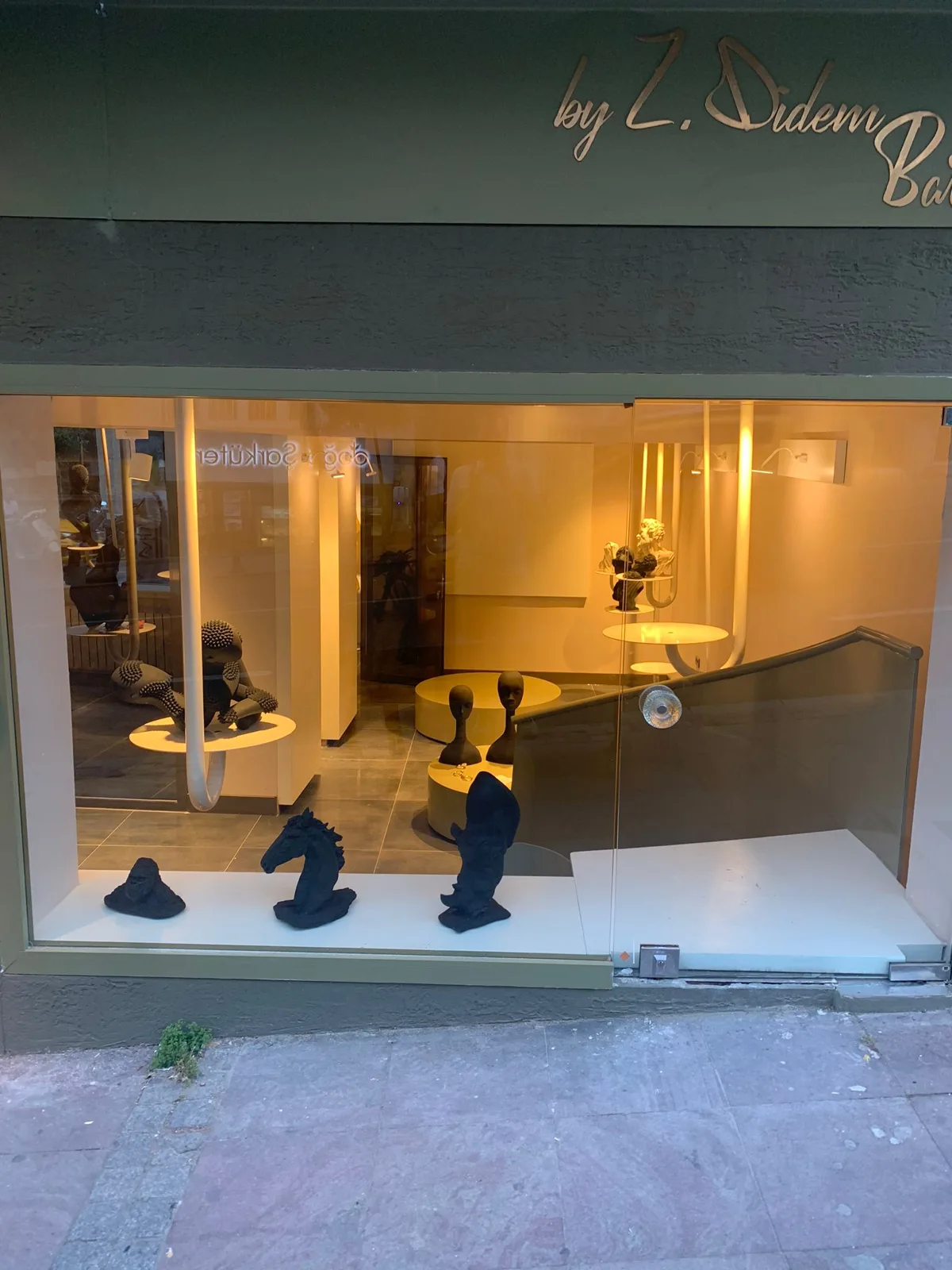 Art & More gallery window with sculptures in evening light — Zeynep Didem Bardakcı
