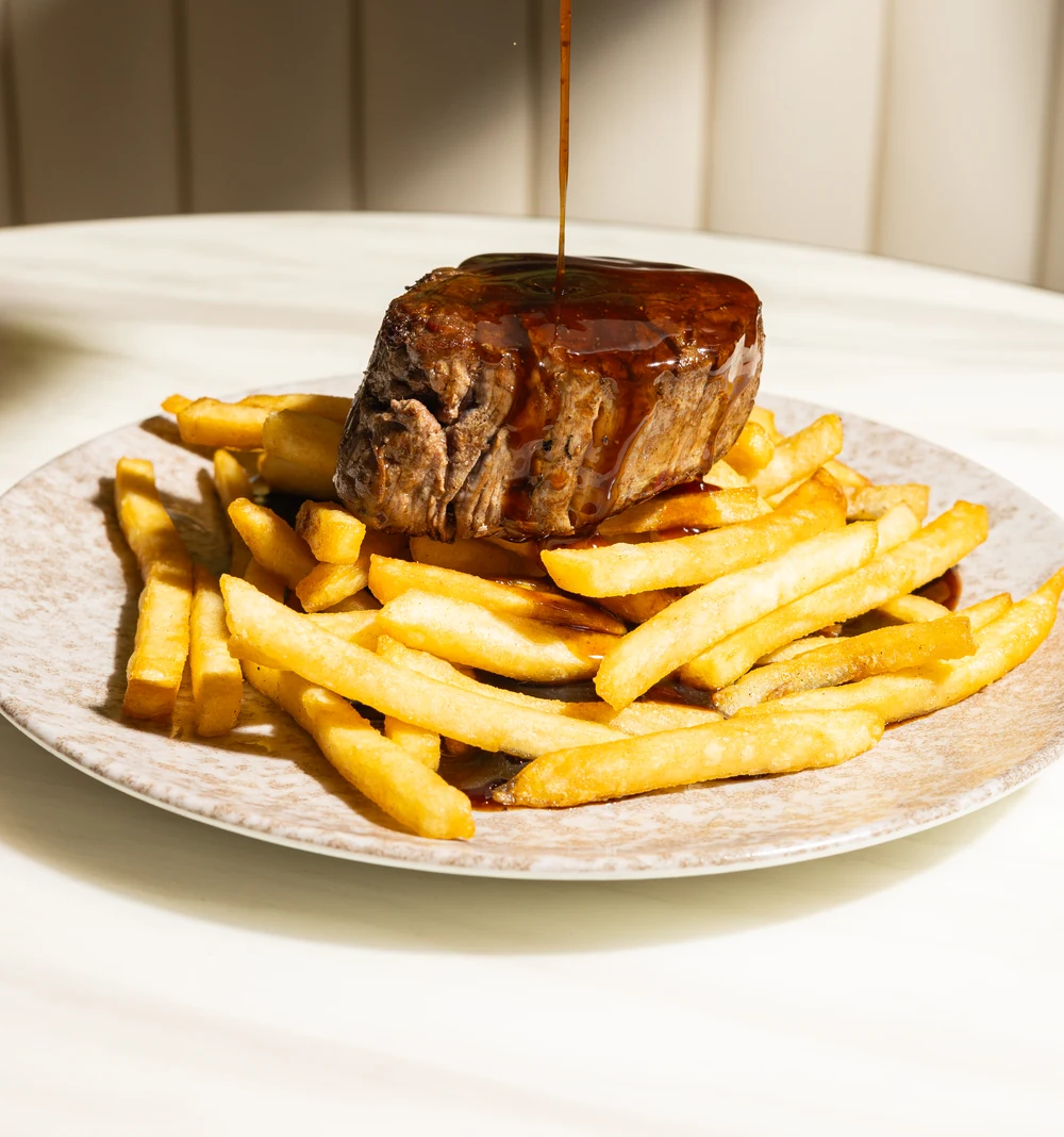 Steak with golden fries and sauce at Amand.