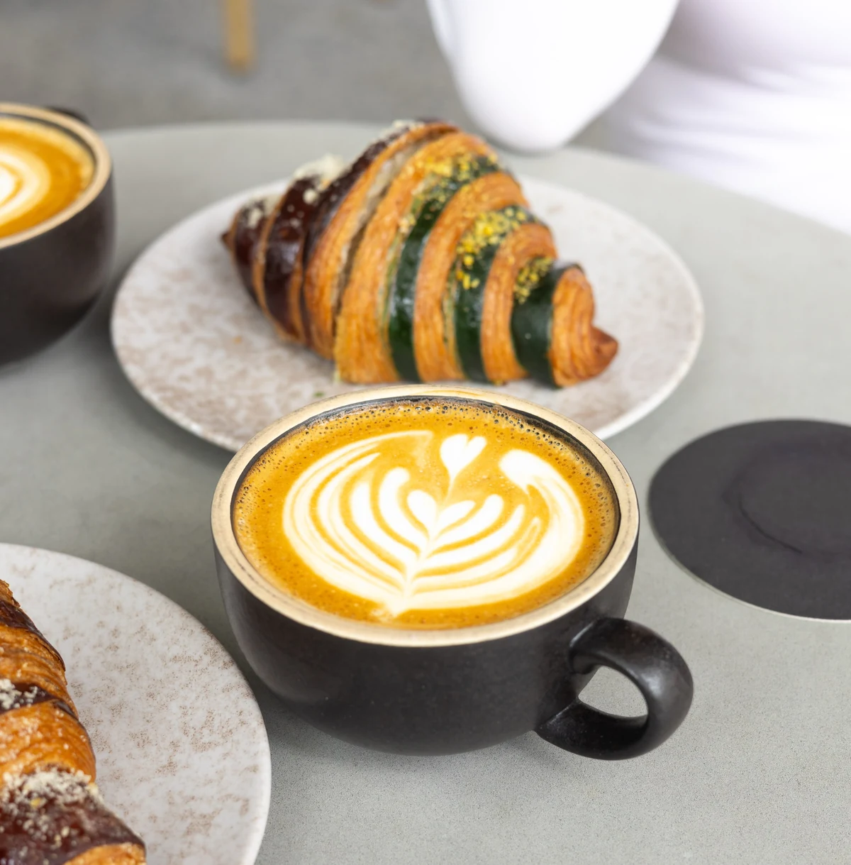 Latte with leaf latte art and croissants at Amand.