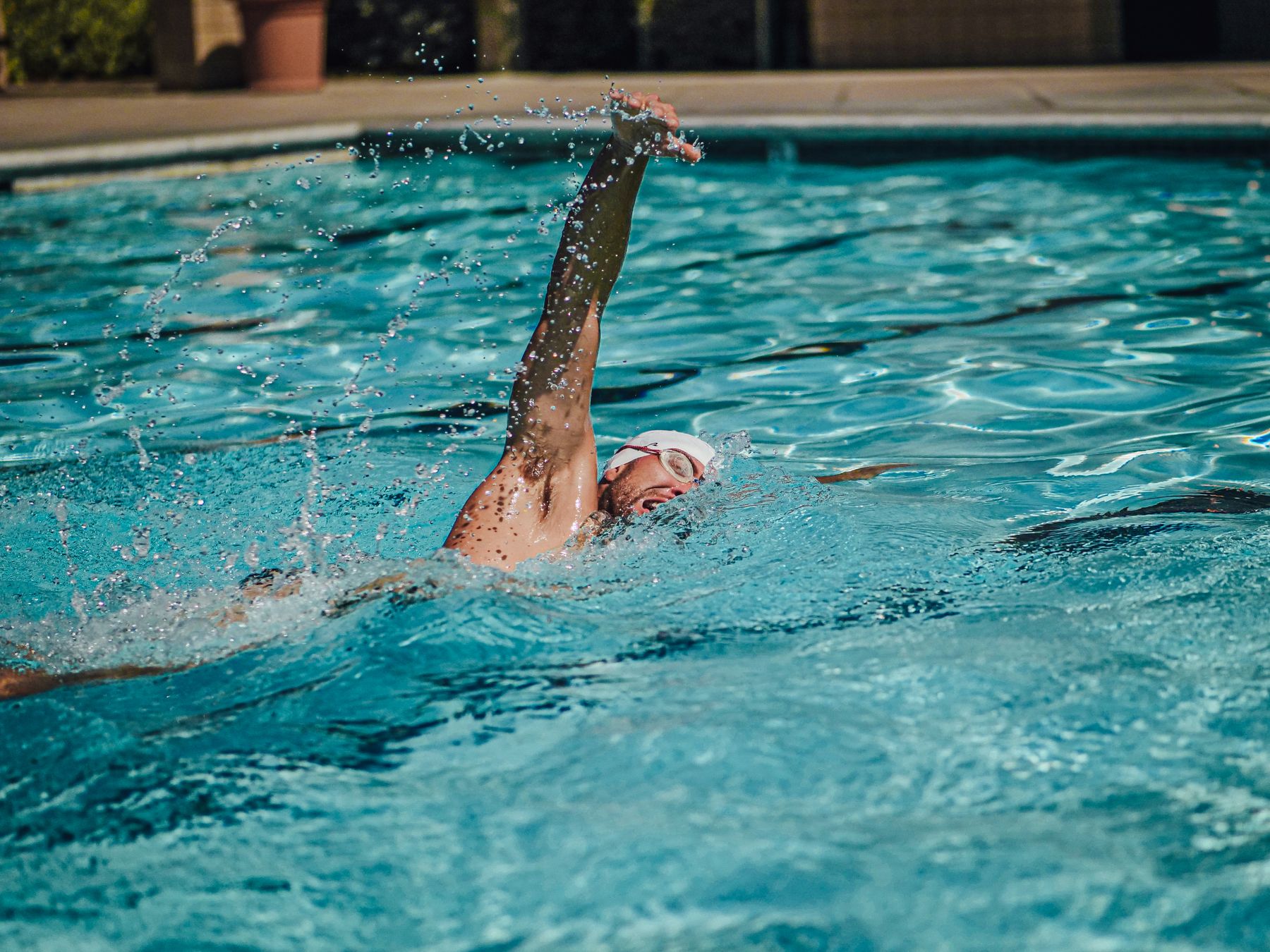 Swimmer practicing backstroke in an outdoor pool