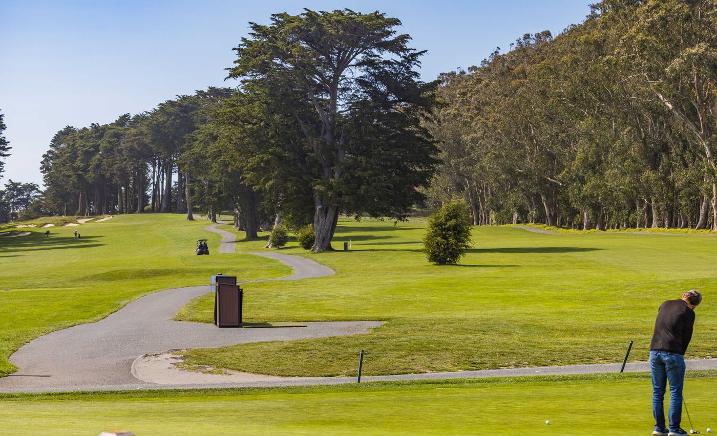 Wide golf course view with a golfer playing a shot