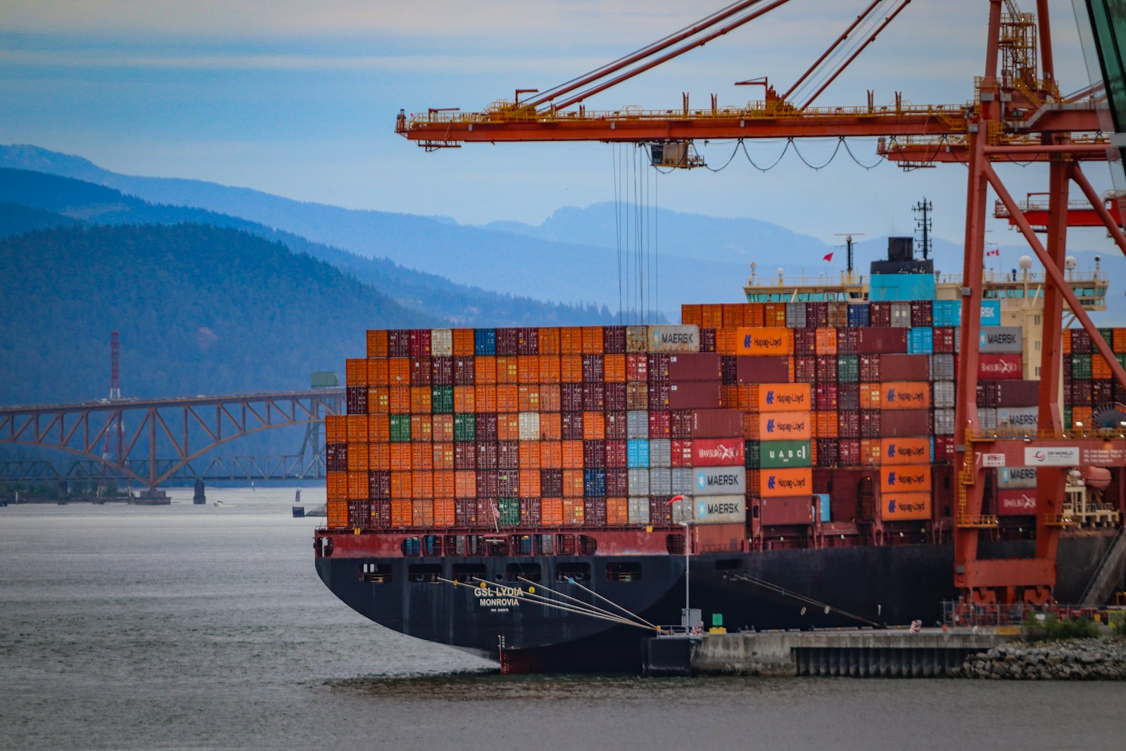 Containerschiff mit bunten Containern unter Hafenkränen