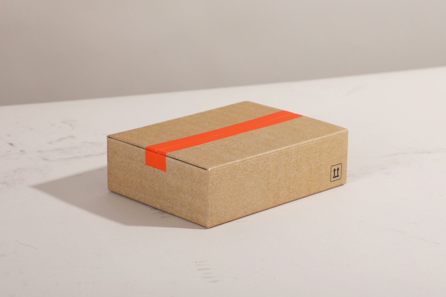 Brauner Versandkarton mit orangefarbenem Klebeband