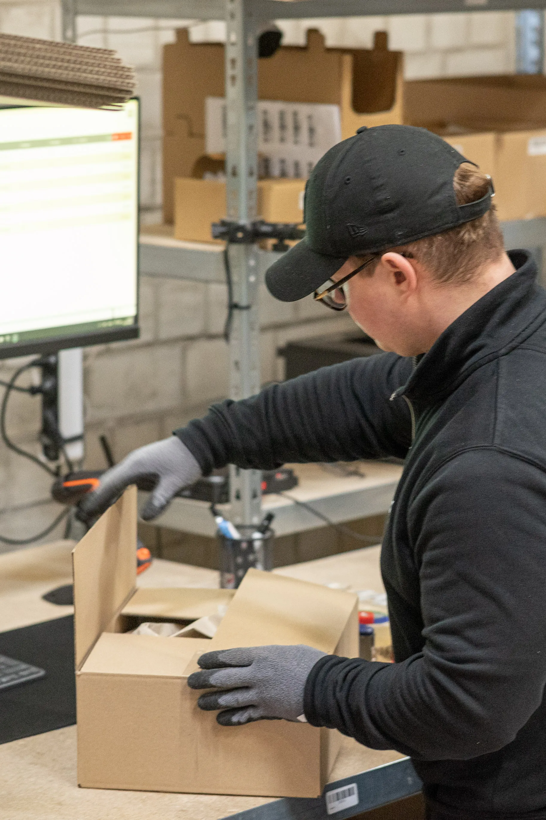 FulFy-Mitarbeiter verpackt eine Bestellung am Packtisch