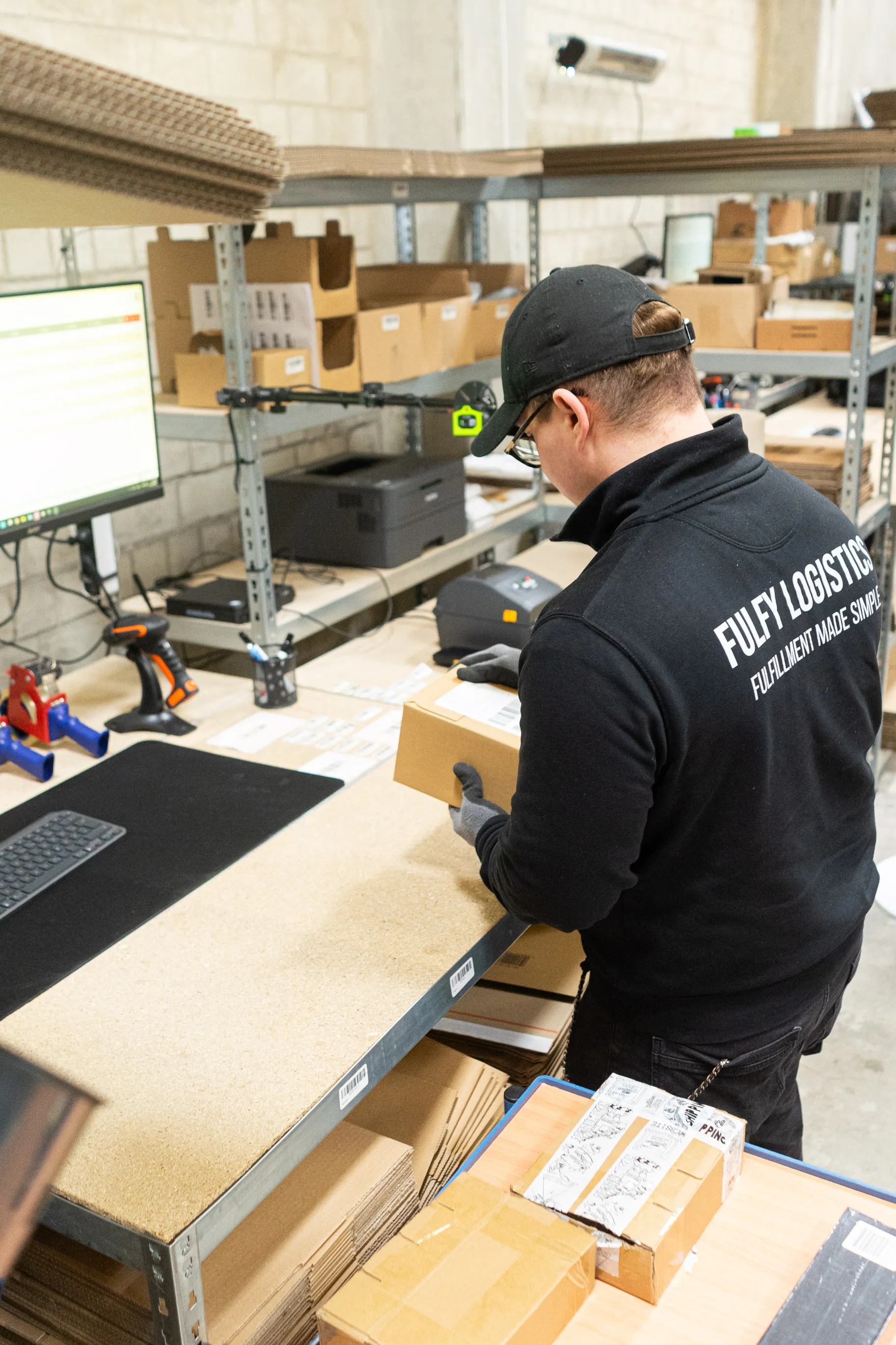 Ein FulFy-Mitarbeiter verpackt eine Bestellung am Packtisch