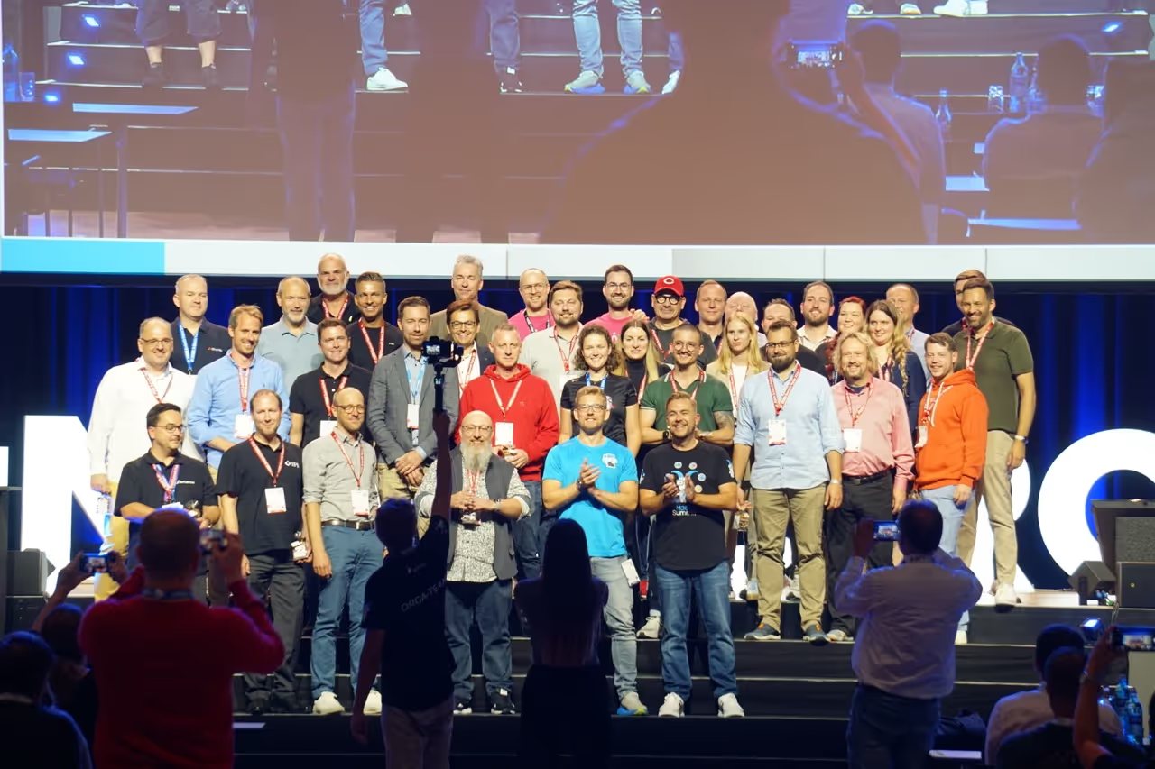 Das Orga-Team und die Speaker des M365 Summit stehen nach einer Session in großer Gruppe auf der Mainstage; im Vordergrund filmen Teilnehmende mit dem Smartphone.