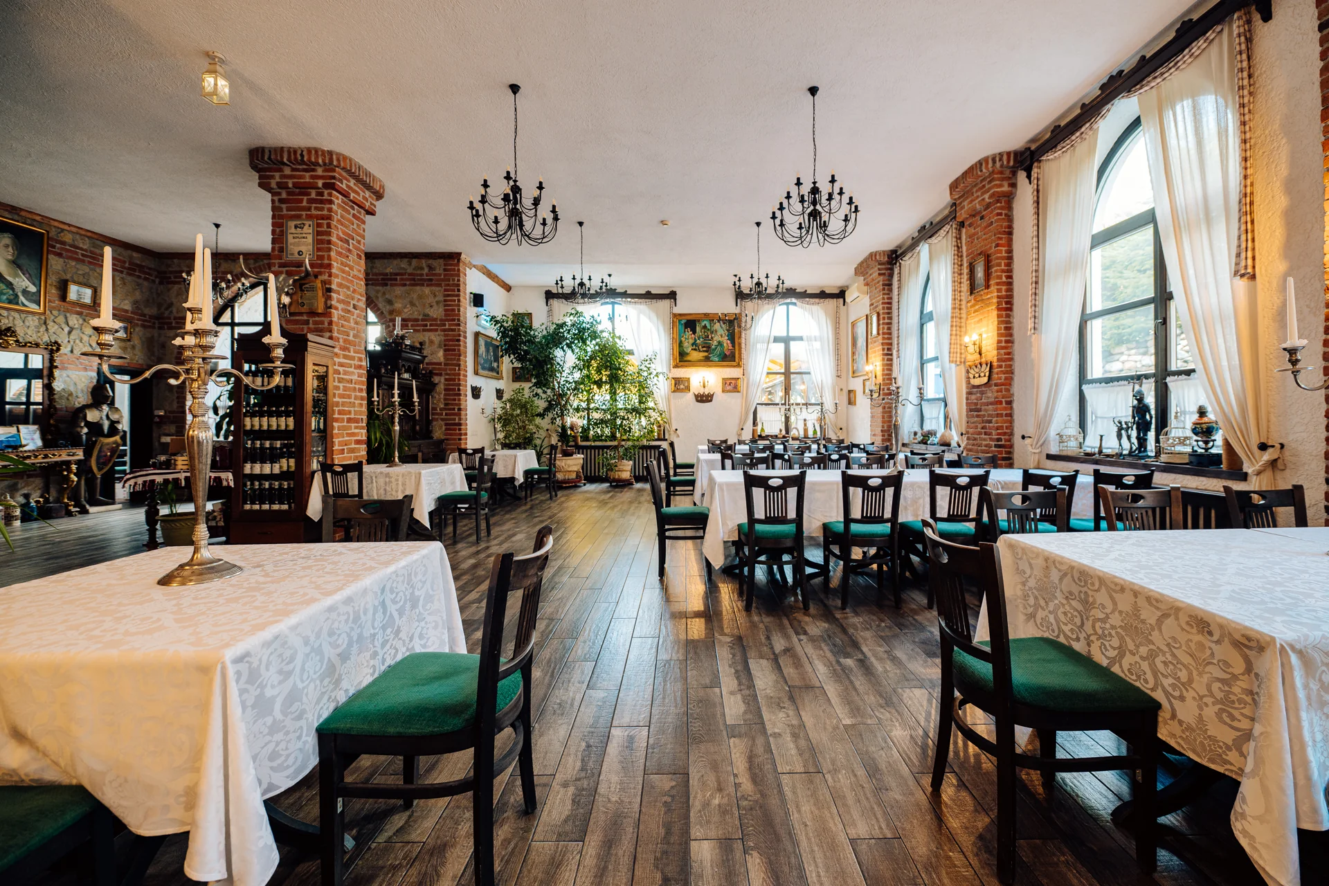 Restaurantul Conacului Maria Theresa, cu ferestre înalte, coloane de cărămidă și mese pregătite