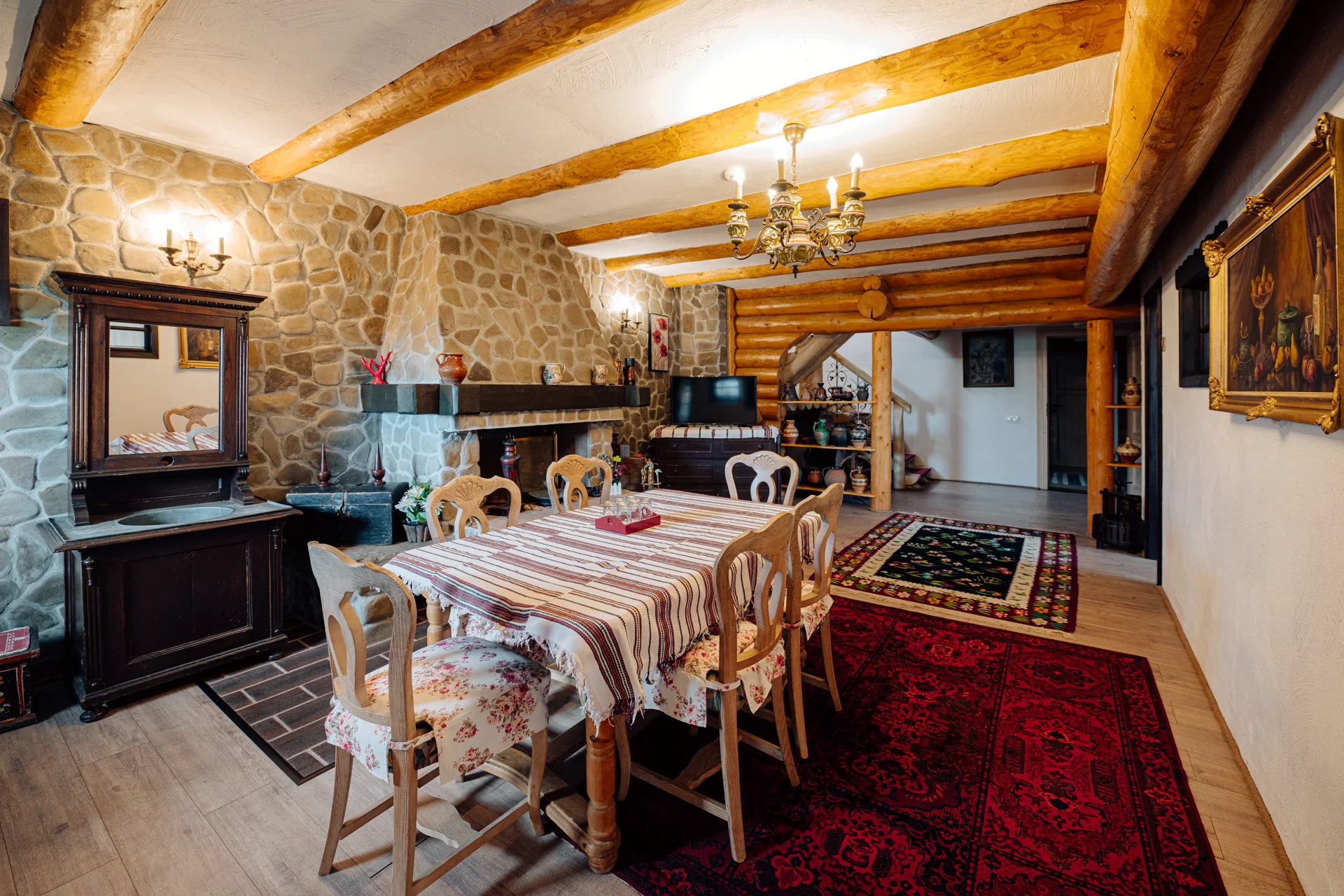 Interior al Conacului Maria Theresa, cu grinzi din lemn, șemineu de piatră și mobilier tradițional