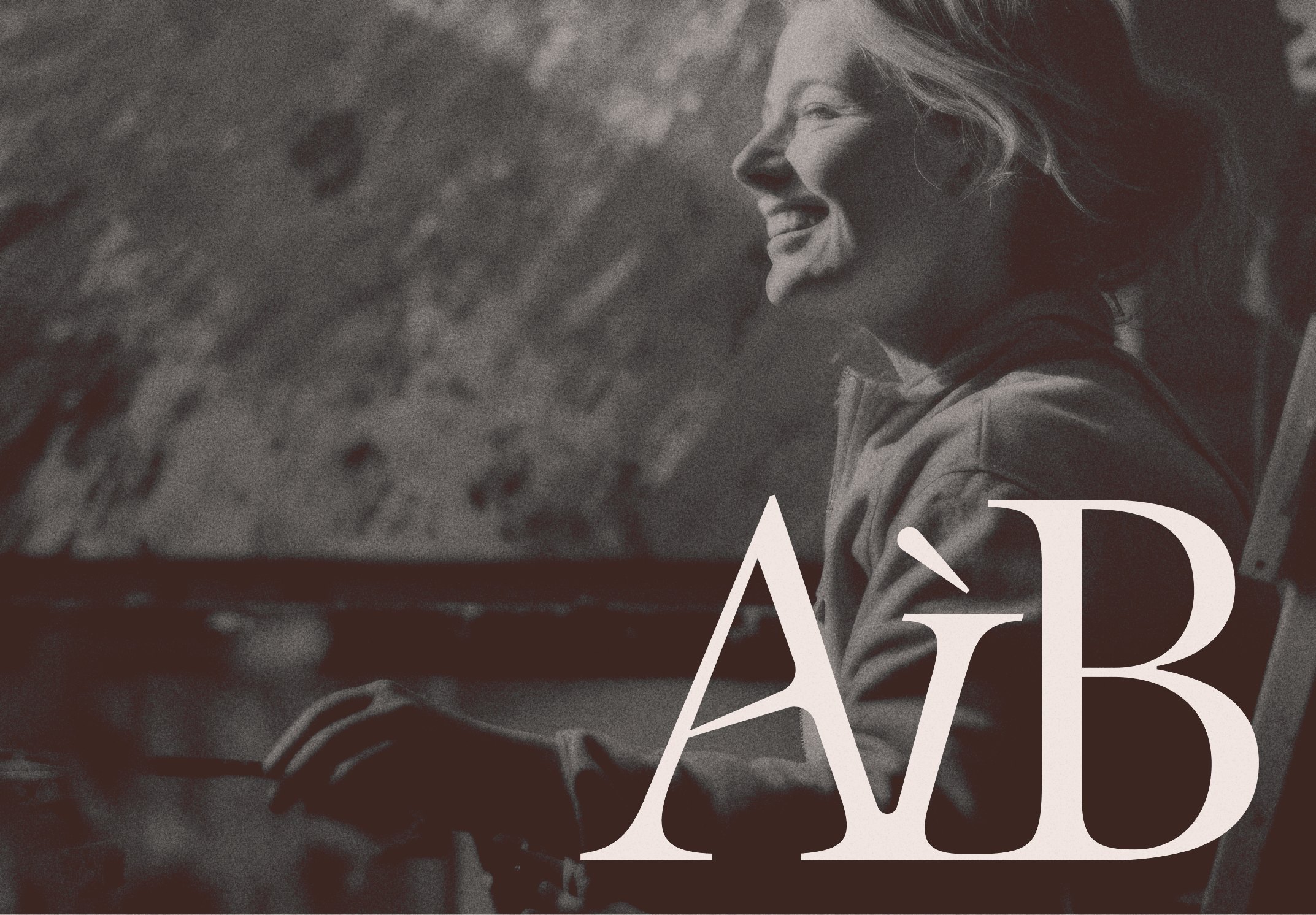 An artist smiling at her easel, with the AiB monogram