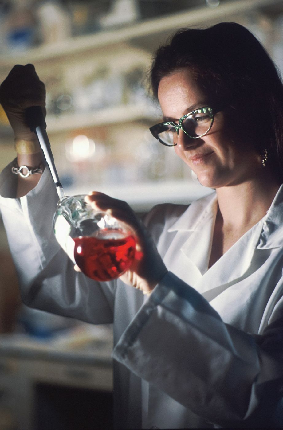 Scientist in a lab coat examining a flask