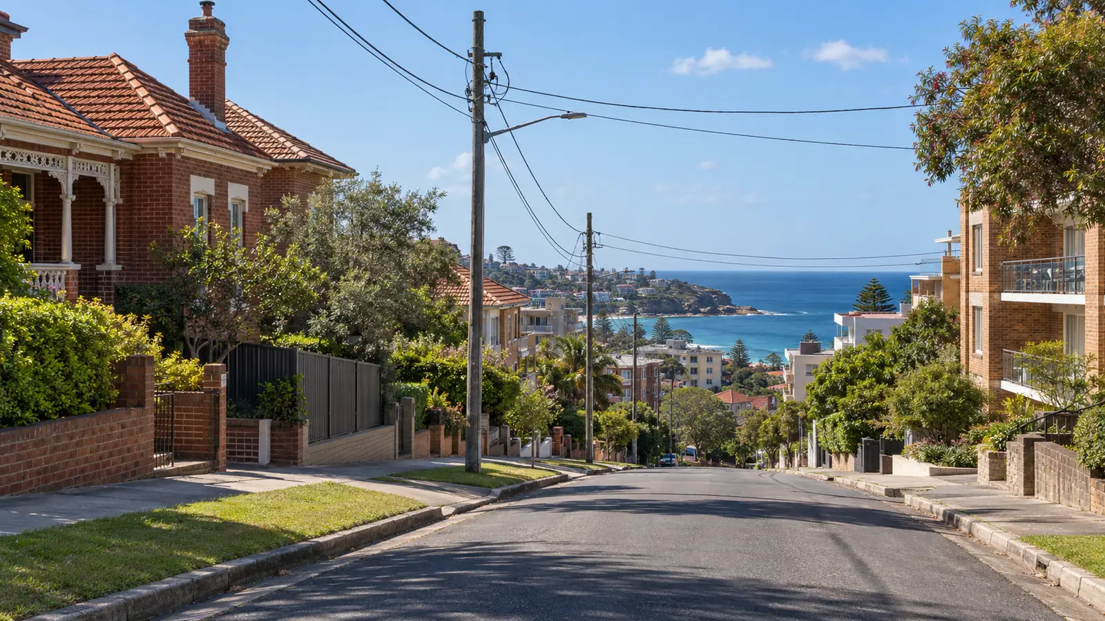 Hilly Eastern Suburbs street with overhead power lines and an ocean view
