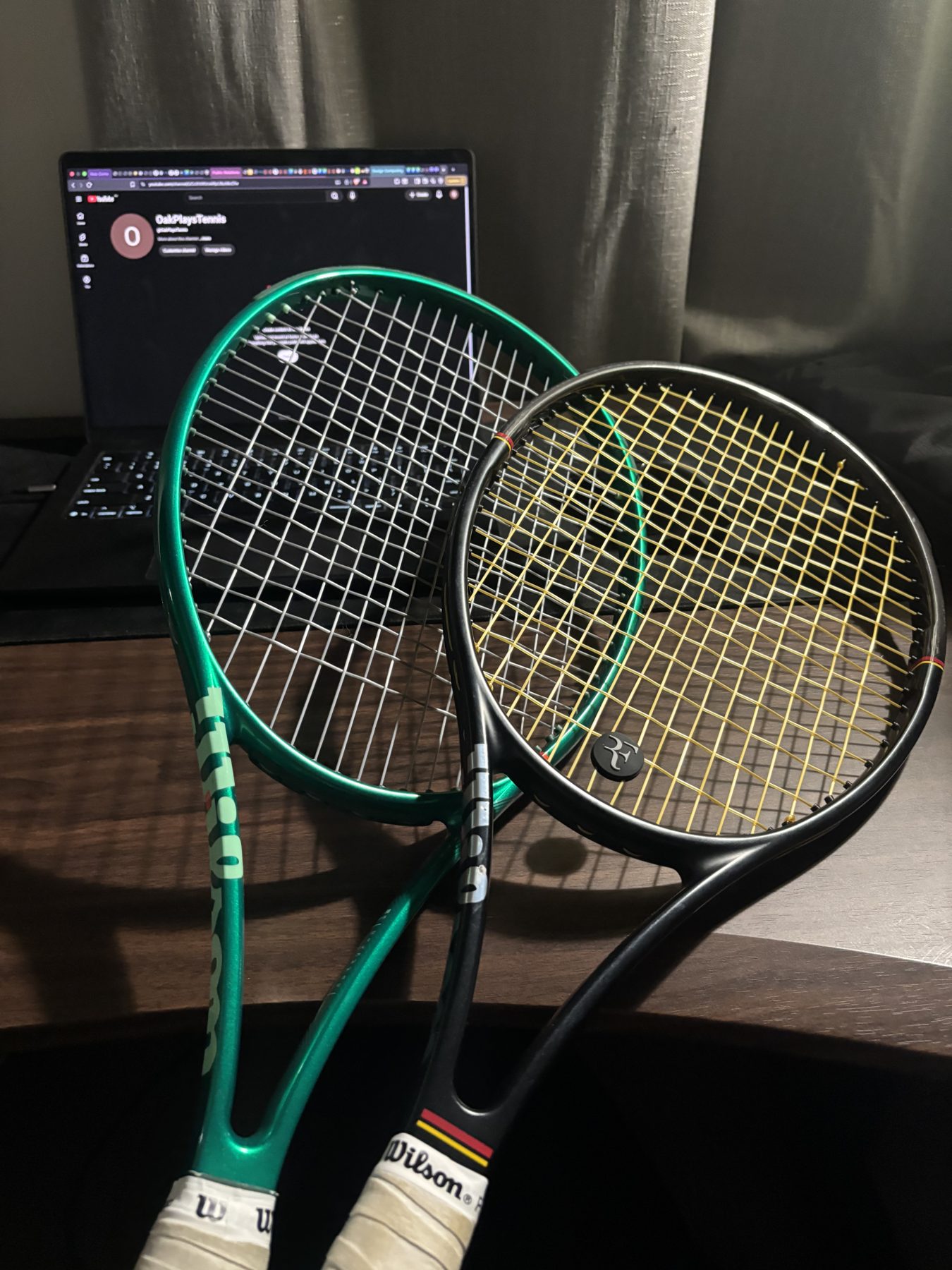 Two Wilson tennis rackets, one green and one black, with white overgrips