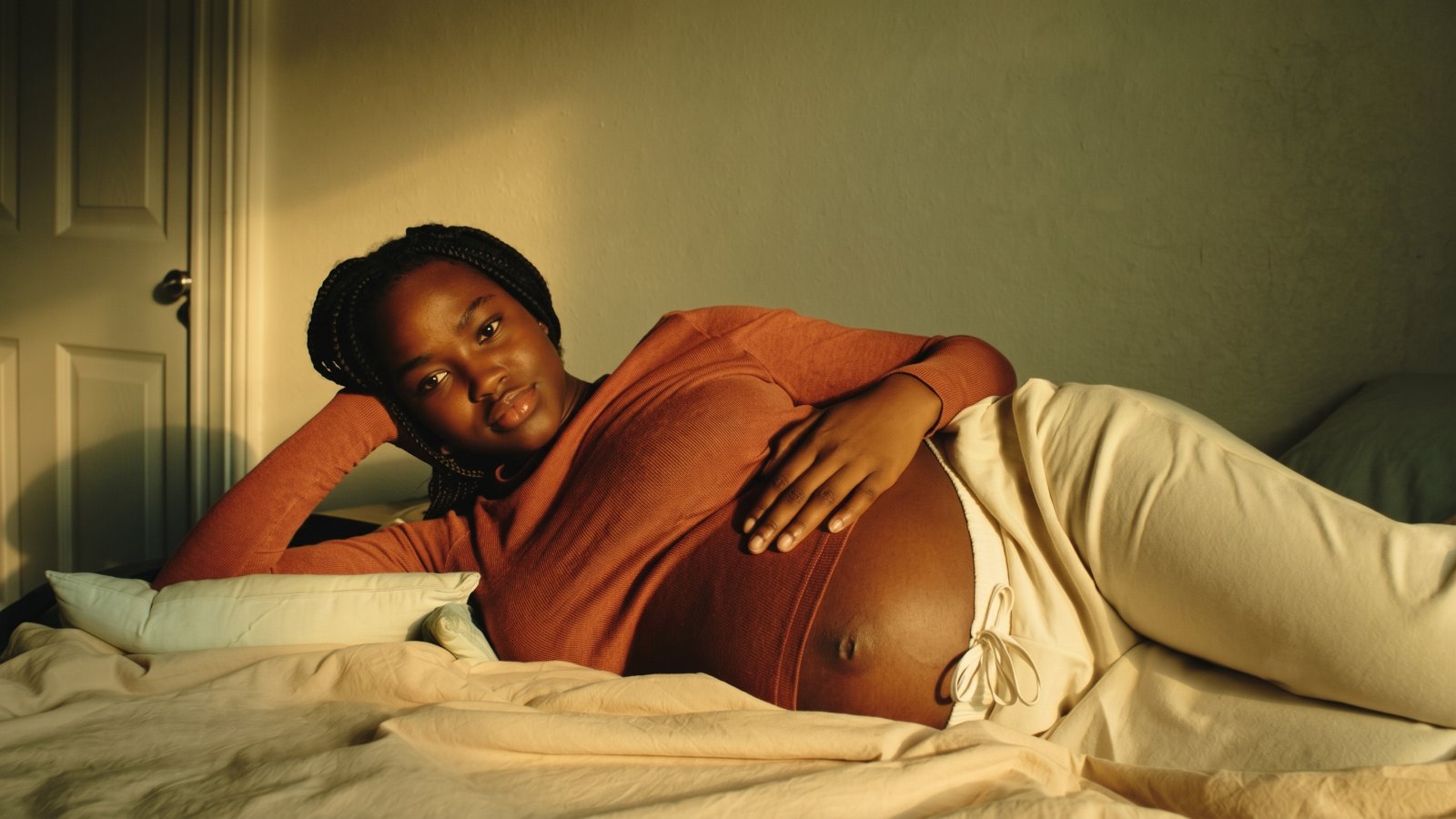A pregnant woman rests on her side in warm evening light