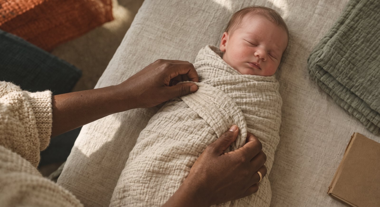 A newborn sleeps wrapped in a soft swaddle