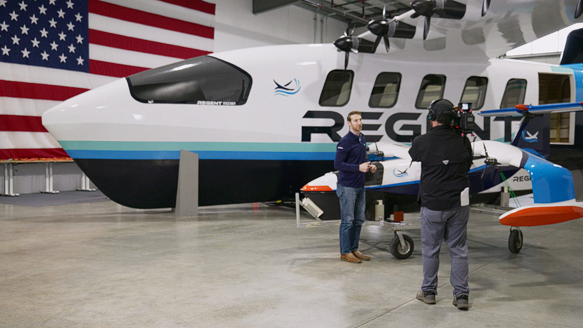 Travis Andrews filming REGENT co-founder and CEO Billy Thalheimer in front of full-scale Seaglider mock-ups at the REGENT facility.