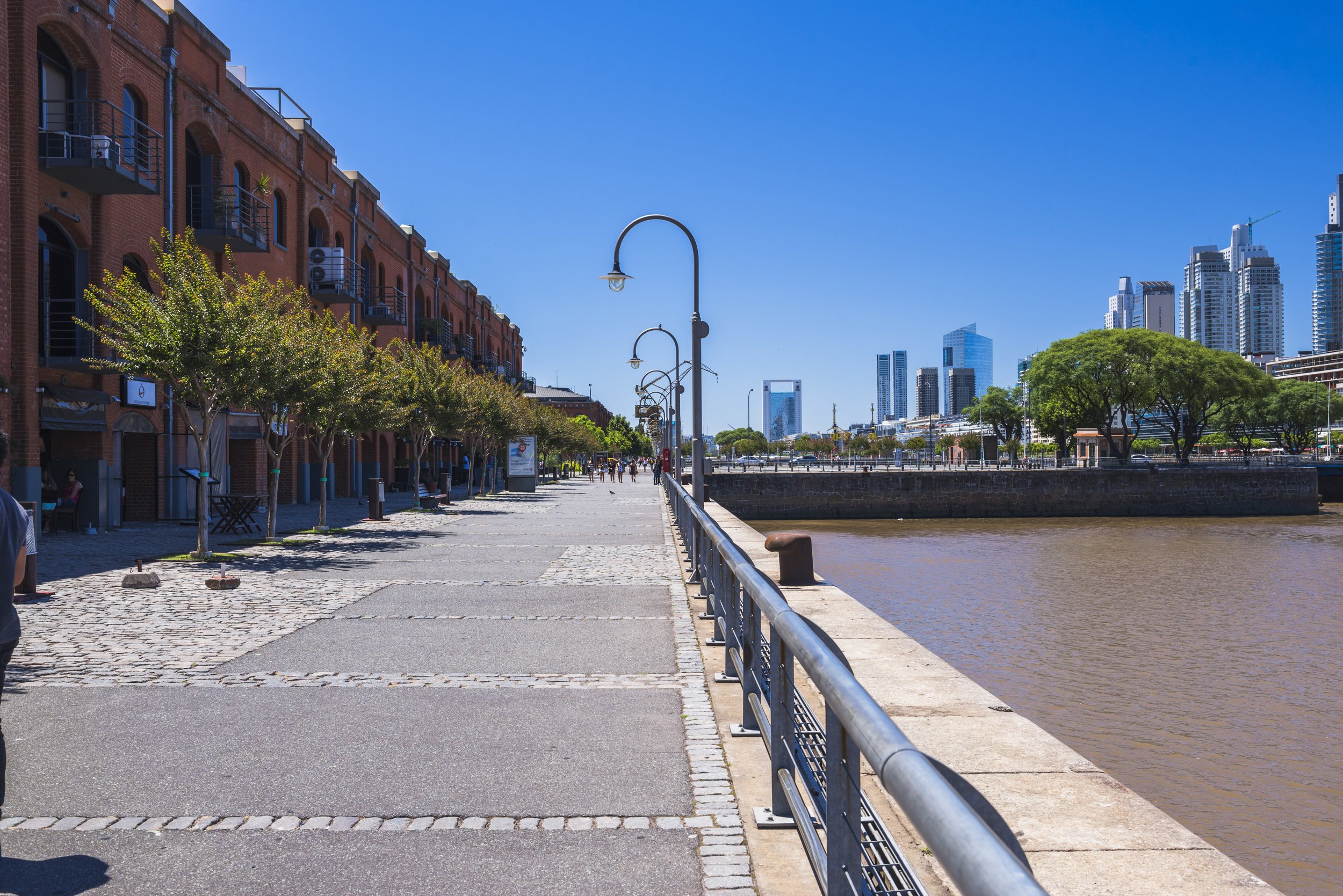 Paseo peatonal y dique de Puerto Madero junto a los antiguos docks de ladrillo y modernos rascacielos.