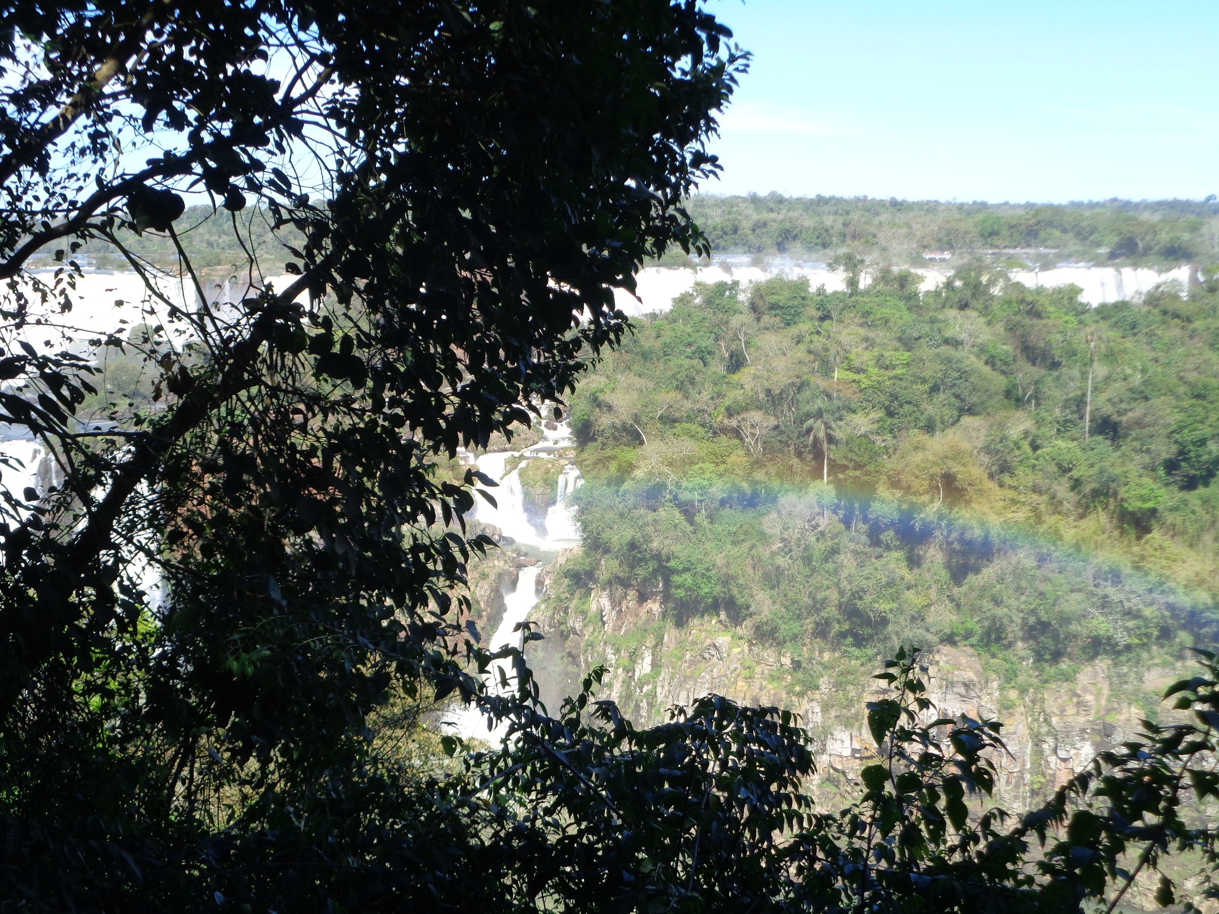 Vista panorámica de saltos de agua y selva con un arcoíris en las Cataratas del Iguazú.