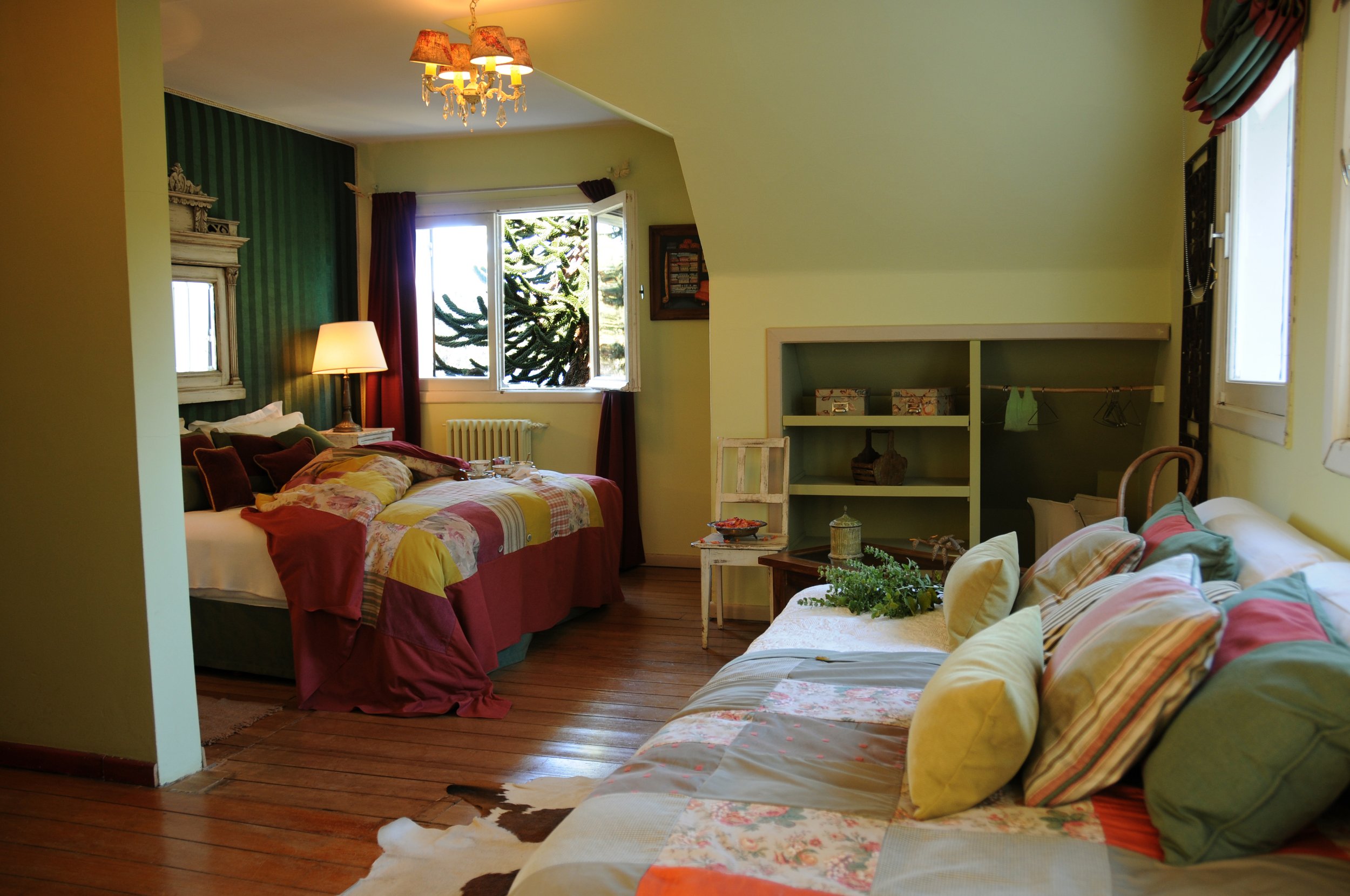 Habitación luminosa de estilo rústico con dos camas, pisos de madera y ventana con vista a araucarias.