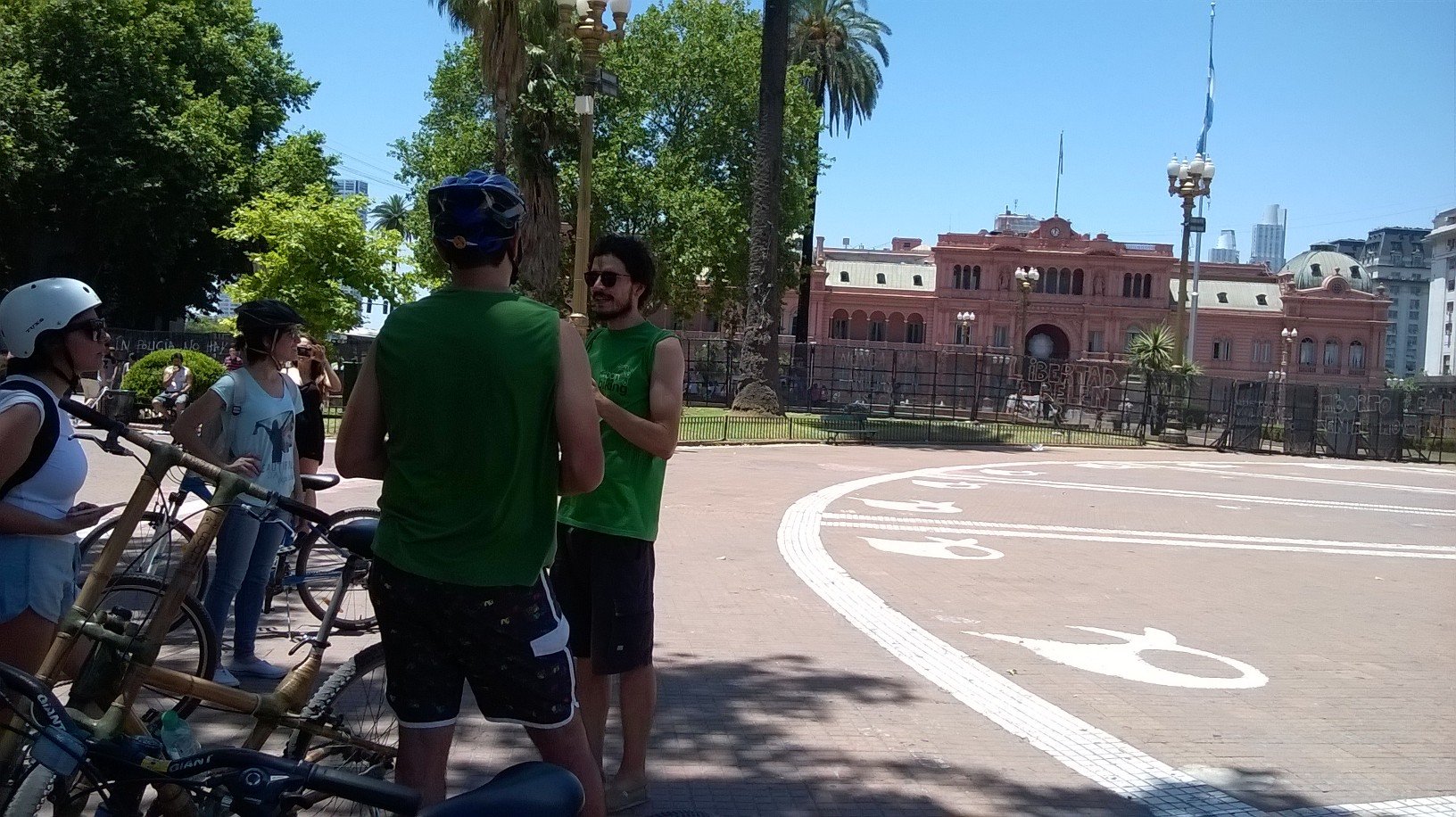 Ciclistas con cascos conversan en la Plaza de Mayo frente a la Casa Rosada en Buenos Aires.