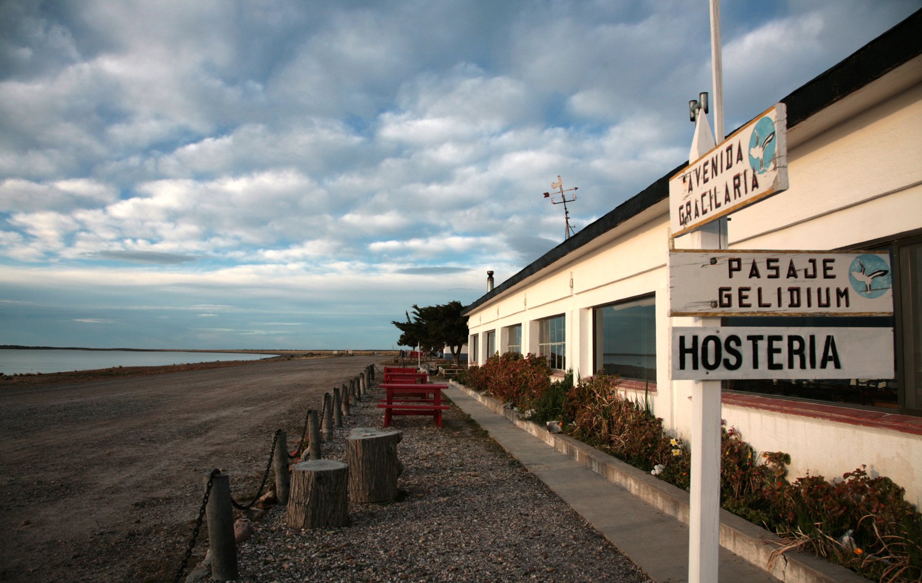 Fachada de la hostería de Bahía Bustamante frente a la costa con carteles rústicos señalizadores de calles.