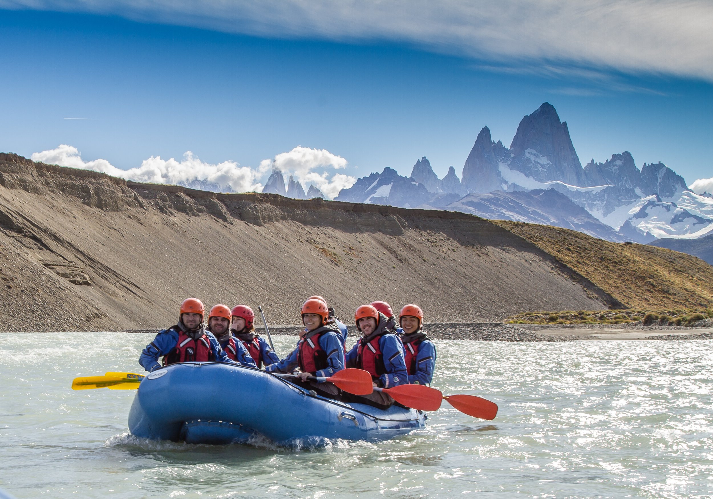 Grupo de personas practicando rafting en un río con el Cerro Fitz Roy de fondo.