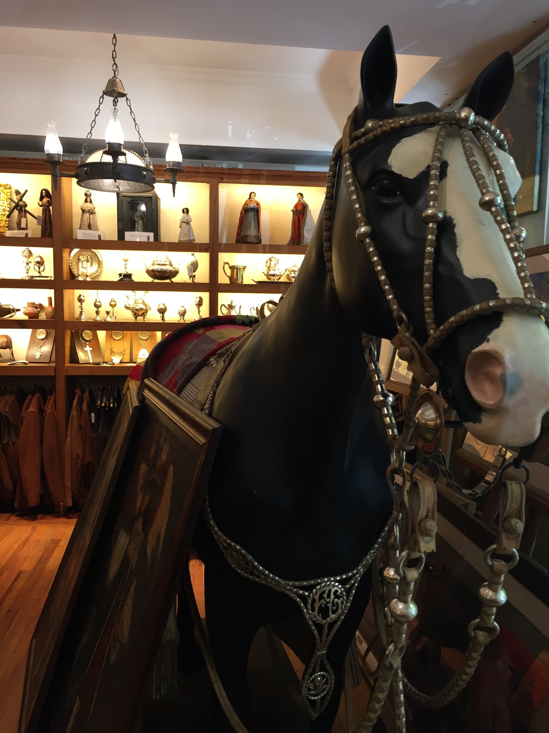 Estatua de caballo con apero criollo y platería en el interior de una tienda de antigüedades.