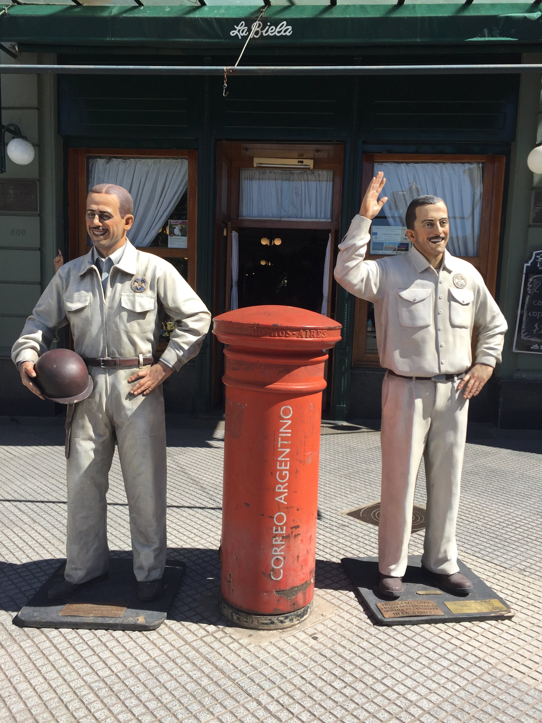 Esculturas y antiguo buzón rojo de correo en la vereda frente al tradicional café La Biela en Recoleta.